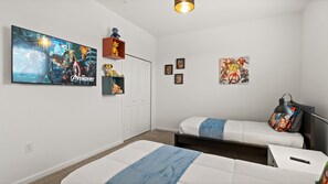 Ein Schlafzimmer mit zwei Betten, einem Fernseher, der den Film 'Avengers' zeigt, und Superhelden-Dekorationen.