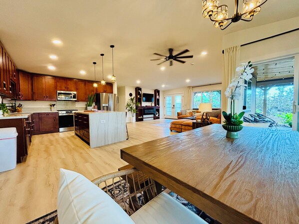 Una cocina amplia con armarios de madera, una isla central y una zona de comedor con una gran mesa de madera.