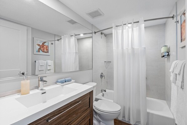 A modern bathroom with a white sink, wooden vanity, a toilet, and a shower with a glass door.