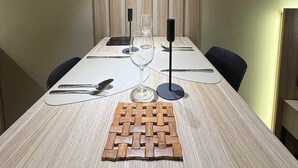Ein Esstisch mit gewebter Tischmatte, Weingläsern, Besteck und Servietten.