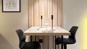 A modern dining area with a wooden table, two black bar stools, and a framed artwork on the wall. - Altimera Collection - Poise - Ski-In/Ski-Out (Dusheti Municipality)