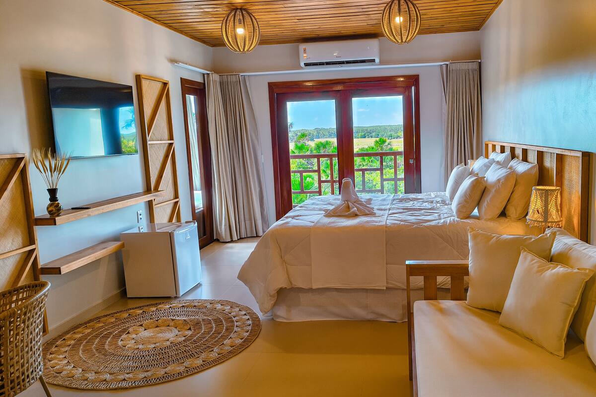Un dormitorio con cama, sofá, televisión y balcón con vistas.