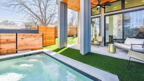 Ein moderner Poolbereich im Freien mit einer Holzterrasse, einer Sitzgelegenheit mit Stühlen und einem Tisch und einem großen Panoramafenster mit Blick auf den Pool.