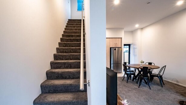 Een trap die leidt naar een eethoek met een tafel, stoelen, een koelkast en een televisie.