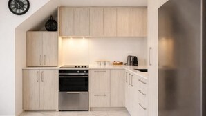 Een moderne keuken met lichte houten kastjes, een roestvrijstalen oven en een inbouwmagnetron.