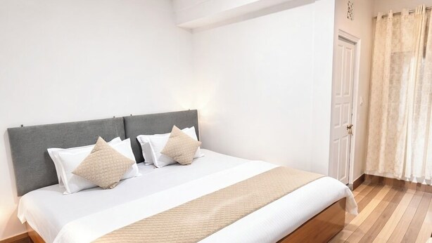 Ein modernes Schlafzimmer mit einem großen Bett, Holzboden und einer neutralen Farbgestaltung.