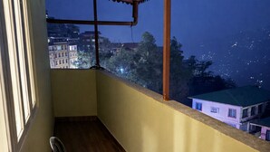 Ein Balkon mit zwei Stühlen und Blick auf die beleuchtete Stadt.