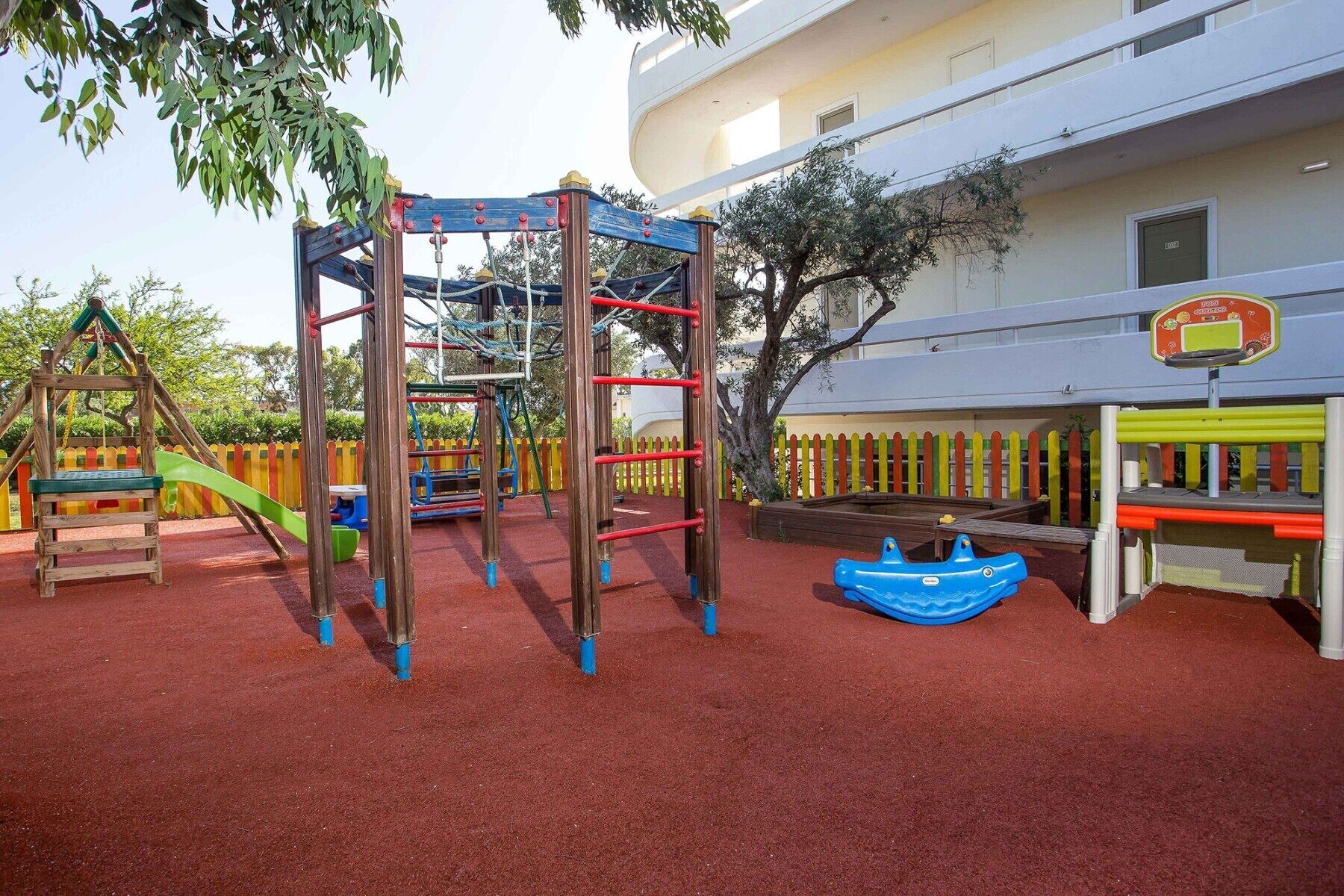 A playground with a climbing structure, a slide, and a swing set.