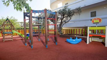 A playground with a climbing structure, a slide, and a swing set.