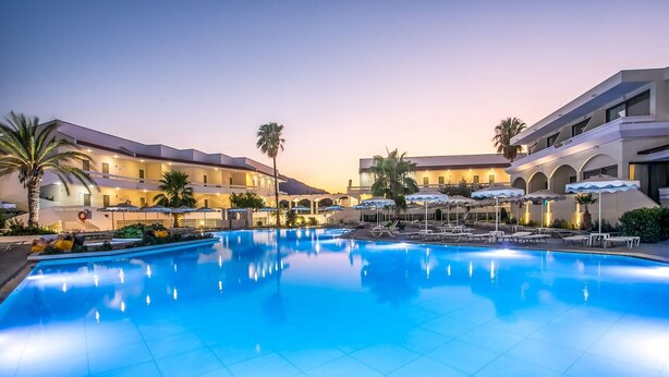 A hotel with a swimming pool, palm trees, and outdoor umbrellas. - Niriides Hotel (Rhodes)