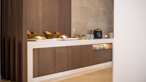 A kitchen area with a wooden cabinet, a countertop, and a coffee machine. - Niriides Hotel (Rhodes)