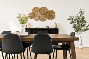 A dining area with a wooden table, black chairs, a decorative wall piece, and a potted plant. - Spa - River - Game Room | Le Boréal (Mont-Tremblant)
