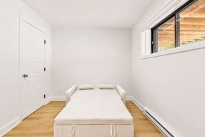 A minimalist room with a bed, a window, and a door. - Spa - River - Game Room | Le Boréal (Mont-Tremblant)