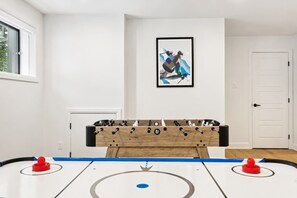 A room with a foosball table, a framed abstract painting on the wall, and a white door. - Spa - River - Game Room | Le Boréal (Mont-Tremblant)
