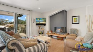 A living room with a fireplace, a television, and a sofa. - Beachcrest Cottage in Twin Lakes Beach (Santa Cruz)