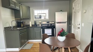 A modern kitchen with grey cabinets, a stainless steel refrigerator, and a dining area with a round table and brown chairs. - Ravenswood Loft - Peaceful 2-bedroom apartment in vibrant Chicago (Chicago)