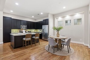 Une cuisine moderne avec des meubles de couleur sombre, un réfrigérateur en acier inoxydable et un îlot central doté de tabourets de bar.