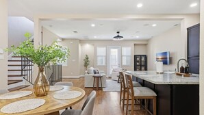 Une cuisine moderne avec un coin repas, un plancher en bois et un escalier.