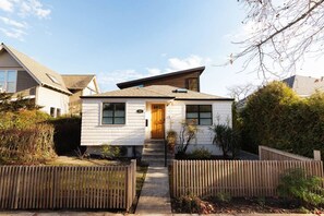Une maison de plain-pied avec une porte d’entrée, un petit porche et le numéro « 212 » peint sur le mur.
