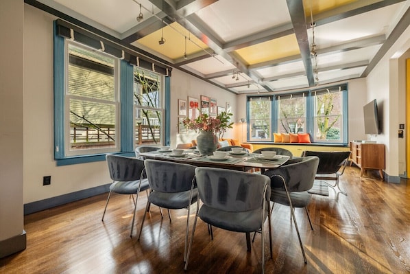 Un comedor con una mesa de madera, seis sillas y un jarrón de flores.