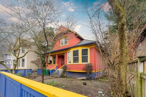 Una casa colorida con fachada roja y amarilla, un pequeño porche y un patio cercado.