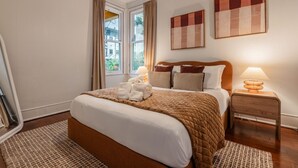 A hotel room with a large bed, two bedside tables, a window with curtains, and artwork on the wall. - NEW The Cap Hill Heartbeat | Walk to Shops & Cafés (Seattle)