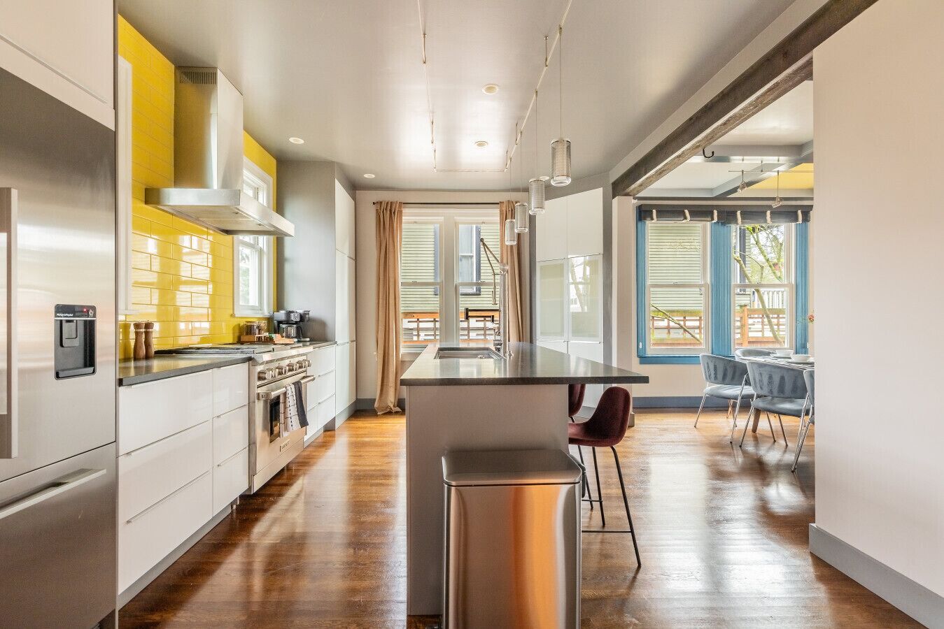 A modern kitchen with stainless steel appliances, a central island, and a dining area with a view.