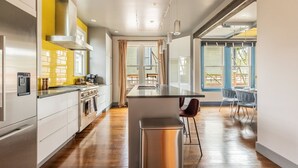 A modern kitchen with stainless steel appliances, a central island, and a dining area with a view. - NEW The Cap Hill Heartbeat | Walk to Shops & Cafés (Seattle)