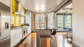 A modern kitchen with stainless steel appliances, a central island, and a dining area with a view.
