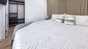 A modern bedroom with a large bed, a built-in wardrobe, and a slatted headboard. - Walk to the beach, CURATED 1-bedroom guesthouse, KING BED, EV charger (Huntington Beach)