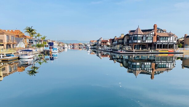 A waterfront property with a canal, boats, and buildings with balconies. - Walk to the beach, CURATED 1-bedroom guesthouse, KING BED, EV charger (Huntington Beach)