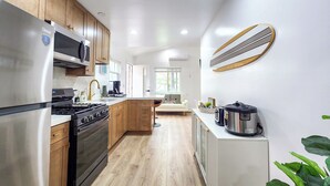A modern kitchen with stainless steel appliances, wooden cabinets, and a white countertop. - Walk to the beach, CURATED 1-bedroom guesthouse, KING BED, EV charger (Huntington Beach)