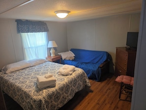 A bedroom with a bed, a nightstand, a dresser, a chair, and a television.
