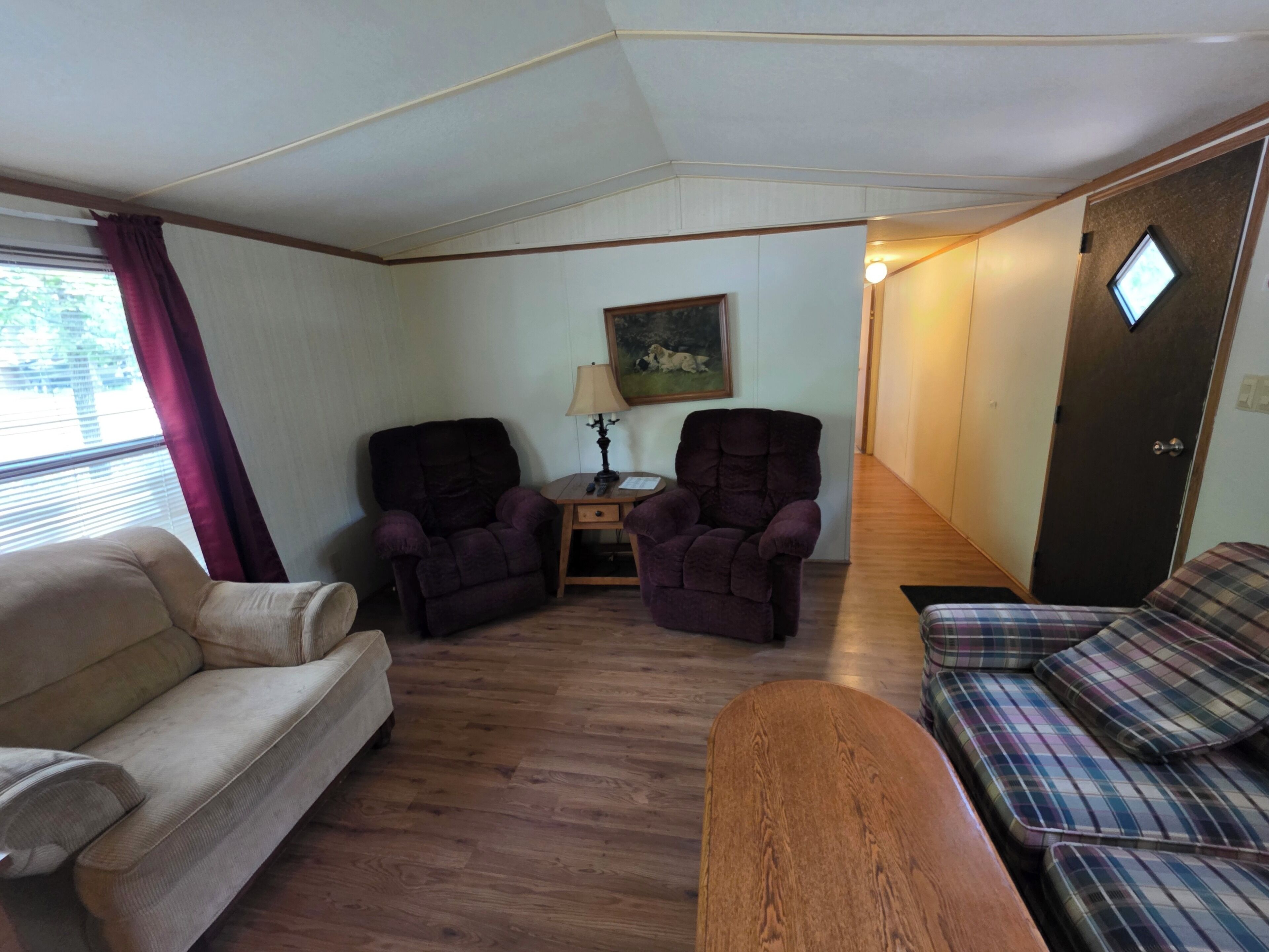Habitació amb un sofà, dues butaques, una taula baixa de fusta, una làmpada i un quadre penjat a la paret.