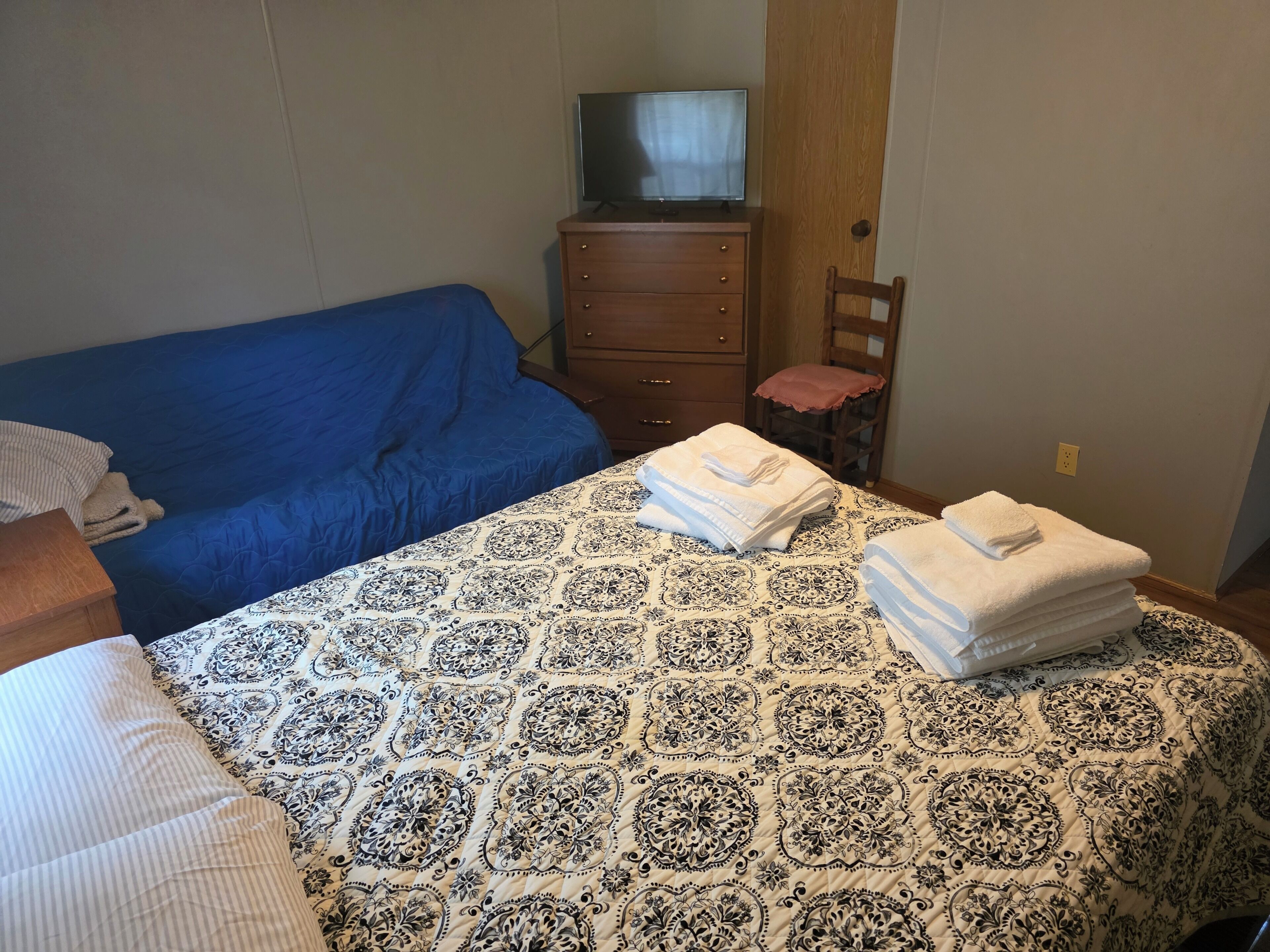 Een slaapkamer met een bed, een kaptafel, een stoel en een televisie.