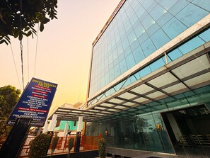 A modern hotel with a glass facade and a sign listing amenities including a conference hall, restaurant, and beauty salon. - Hotel Ranjana Palace (Purnia)
