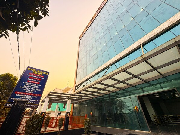 A modern hotel with a glass facade and a sign listing amenities including a conference hall, restaurant, and beauty salon. - Hotel Ranjana Palace (Purnia)