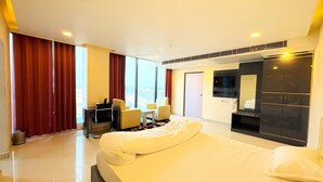 Habitació d'hotel amb un llit gran, un escriptori amb una cadira, un televisor i un armari.
