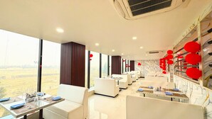 Zona de dinar d'un hotel modern amb mobles blancs, grans finestres i elements decoratius vermells.