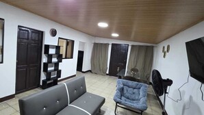 A living room with a sofa, a chair, a TV, and a ceiling fan.