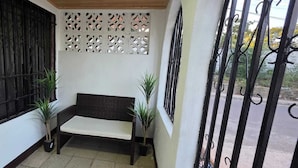 A small outdoor seating area with a bench and two potted plants.