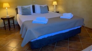 Une chambre d’hôtel comprenant un lit, deux tables de chevet et deux lampes fixées au mur.