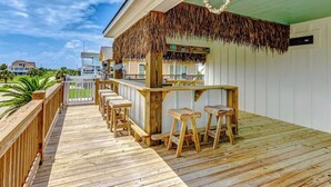 Una terraza de madera con una zona de bar, incluyendo taburetes y barra.