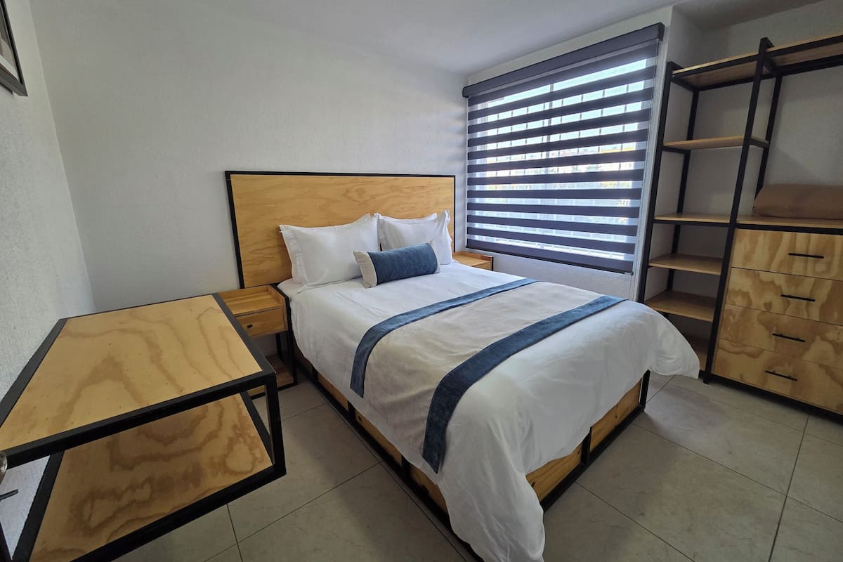 A neatly arranged bedroom with a wooden bed, a bedside table, and a built-in wardrobe.