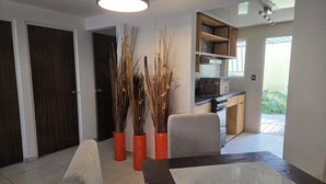 A modern kitchen with a built-in oven and a dining area with a marble table and chairs. - Lofts by Verticca Héroes (Tecamac)
