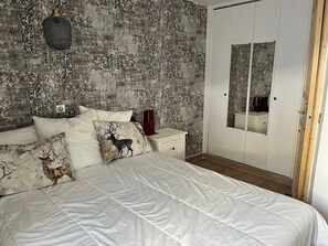 Un dormitorio con cama, mesita de noche, armario y lámpara colgante.