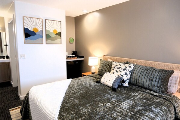 Ein Hotelzimmer mit Bett, Nachttisch, Lampe, einer Uhr und zwei Wandbildern.