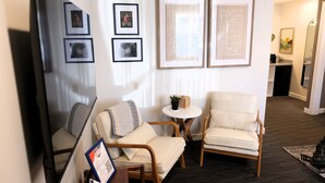 A hotel room with a large flat-screen TV, two armchairs, a small round table, and framed artwork on the wall. - Jackrabbit 133 Downtown Moab Studio | Near Arches National Park | Walk to Shops & Dining (Moab)