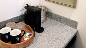 A kitchen with a coffee maker, a clock, and a framed landscape painting. - Jackrabbit 133 Downtown Moab Studio | Near Arches National Park | Walk to Shops & Dining (Moab)