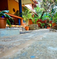 Un patio con plantas en macetas, un muro de piedra y un suelo de baldosas.